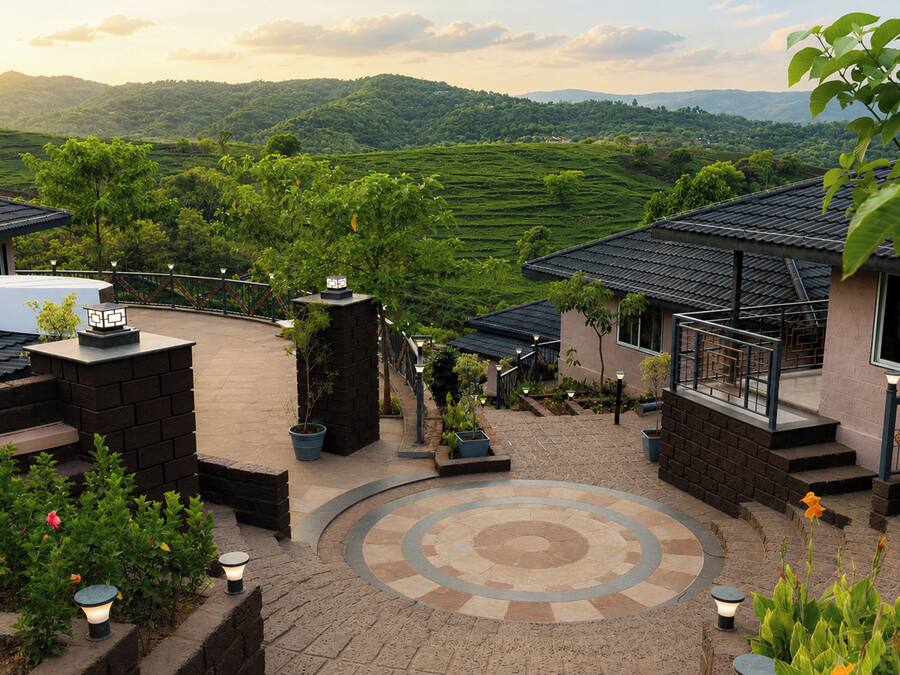 A courtyard with a circular patterned floor, potted plants, and a view of terraced fields in the background.