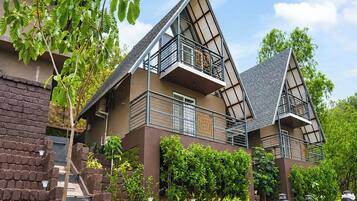 Een modern meerlaags huis met balkon, bakstenen muren en beplanting.