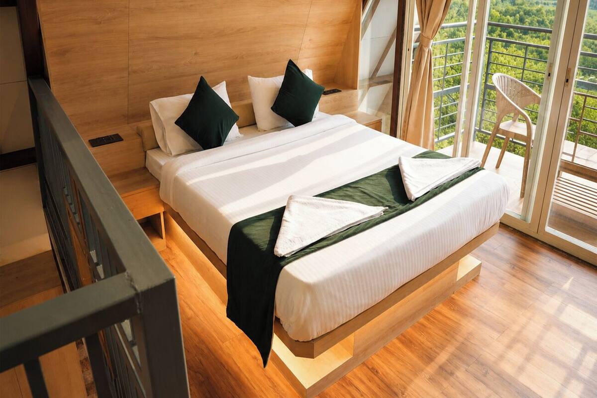 Un dormitorio moderno con dos camas, un balcón con vistas y suelo de madera.