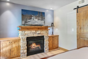 A stone fireplace with a TV above it, wooden cabinets, and a wooden door. - Park City 2BR Condo, Jupiter Inn, Community Hot Tub, Sleeps 6 (Park City)