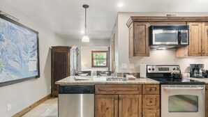 A kitchen with wooden cabinets, stainless steel appliances, and a large map on the wall. - Park City 2BR Condo, Jupiter Inn, Community Hot Tub, Sleeps 6 (Park City)