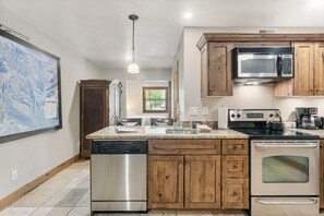 A kitchen with wooden cabinets, stainless steel appliances, and a large map on the wall. - Park City 2BR Condo, Jupiter Inn, Community Hot Tub, Sleeps 6 (Park City)
