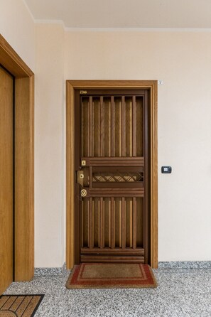 Eine Holztür mit vertikalem Felderdesign, eine Fußmatte und ein an der Wand befestigtes Gerät.