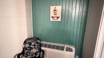 Et hjørneværelse med teal vægge, en hvid radiator, en sort stol med blomstret betræk og et indrammet billede på væggen.
