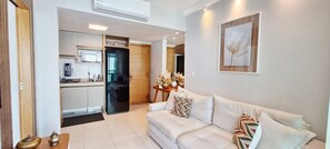 A modern living room with a sofa, a dining area with a table and chairs, and a kitchen with a refrigerator. - COBAR0150 - Edificio Top House (Salvador)