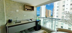 A kitchen with a window view, a built-in shelf, and a refrigerator. - COBAR0150 - Edificio Top House (Salvador)