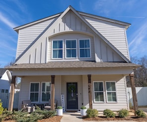 A two-story house with a front porch, a welcome sign, and a front door. - Join us at the Southern Plain Cottage 3-bedroom house close to Auburn campus (Auburn)