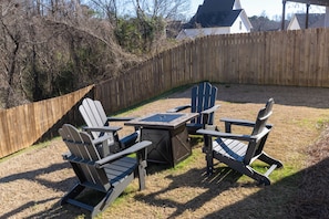 A backyard with a wooden fence, a table, and four Adirondack chairs. - Join us at the Southern Plain Cottage 3-bedroom house close to Auburn campus (Auburn)