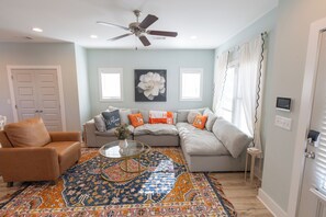 A living room with a sofa, armchair, and a coffee table with a rug. - Join us at the Southern Plain Cottage 3-bedroom house close to Auburn campus (Auburn)