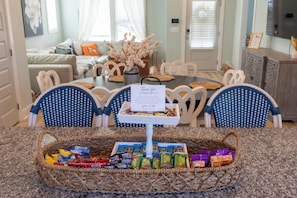 A dining area with a round table, chairs, a basket of snacks, and a thank you sign. - Join us at the Southern Plain Cottage 3-bedroom house close to Auburn campus (Auburn)