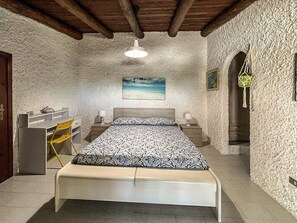 Ein Schlafzimmer mit Bett, Schreibtisch, Stuhl und einer hängenden Pflanze.