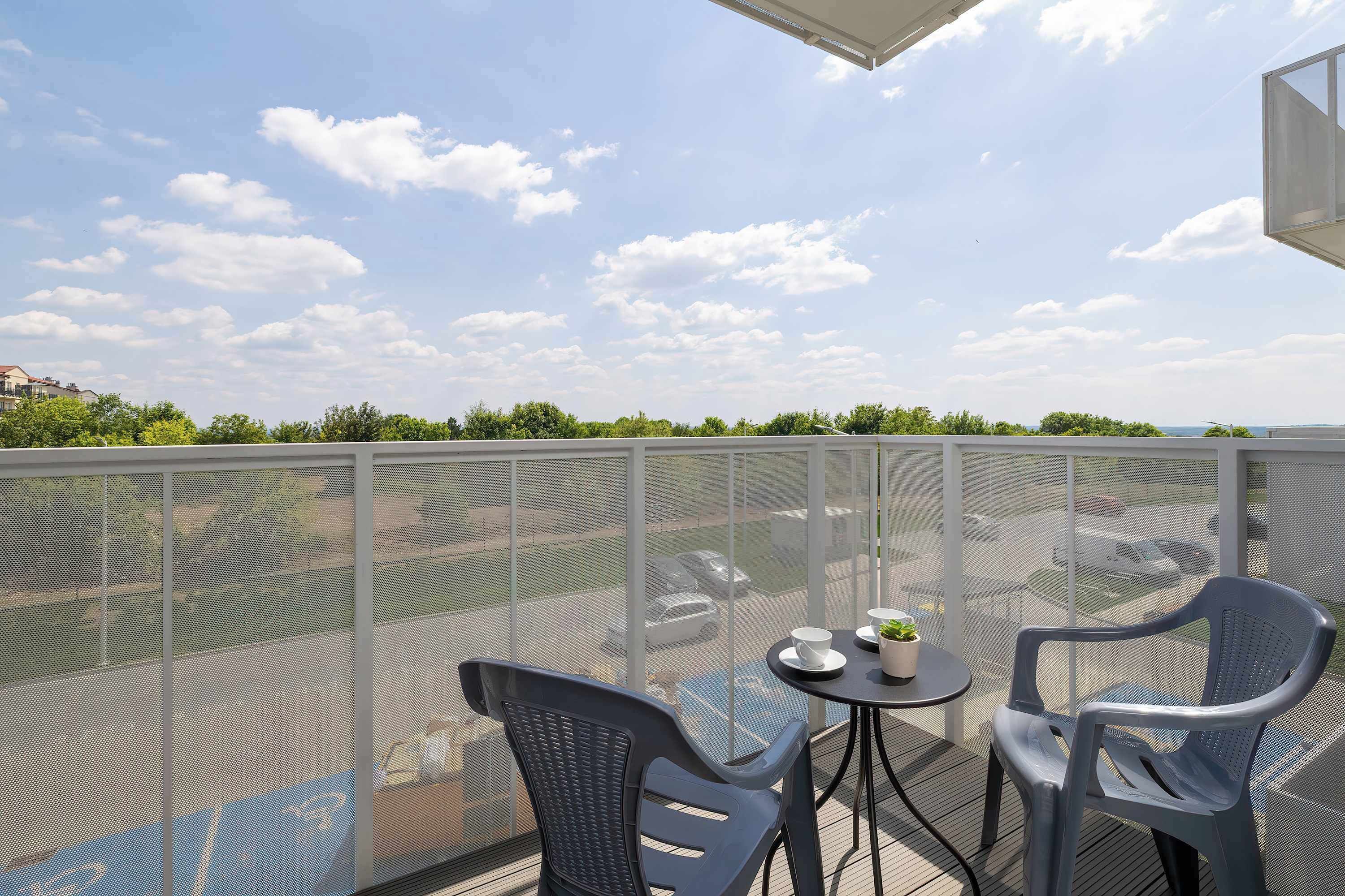 Ein Balkon mit zwei Stühlen, einem kleinen Tisch und einem Blumentopf.