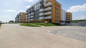 Een meerlaags woongebouw met balkons, een geplaveide binnenplaats en een heldere lucht.