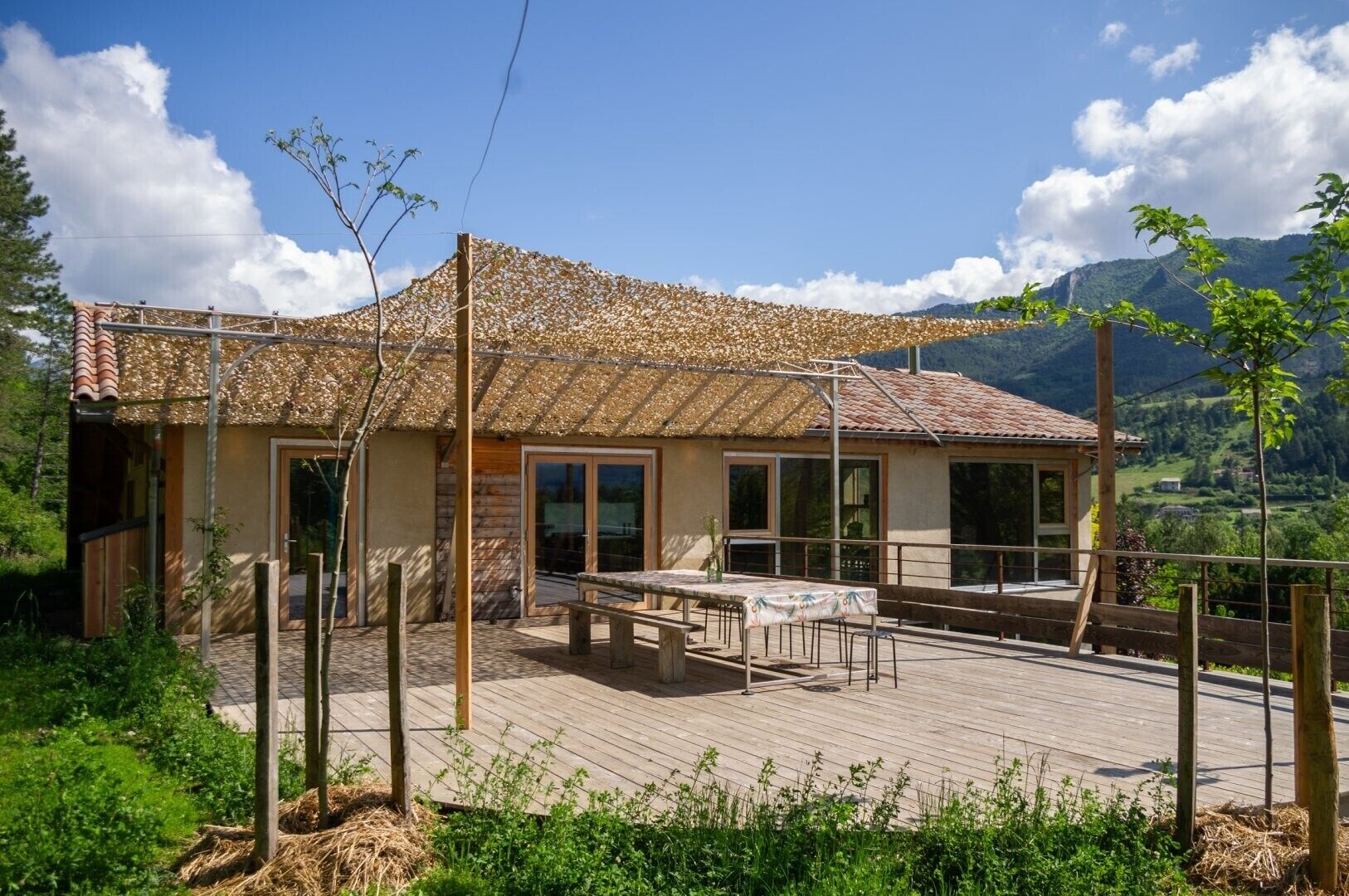 Une terrasse en bois avec une table et des chaises, un patio couvert et une vue sur les montagnes.