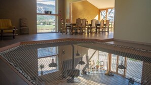 Ein geräumiges Zimmer mit großem Fenster, einer Sitzecke mit Stühlen und einem Poolbereich mit Sicherheitsnetz.