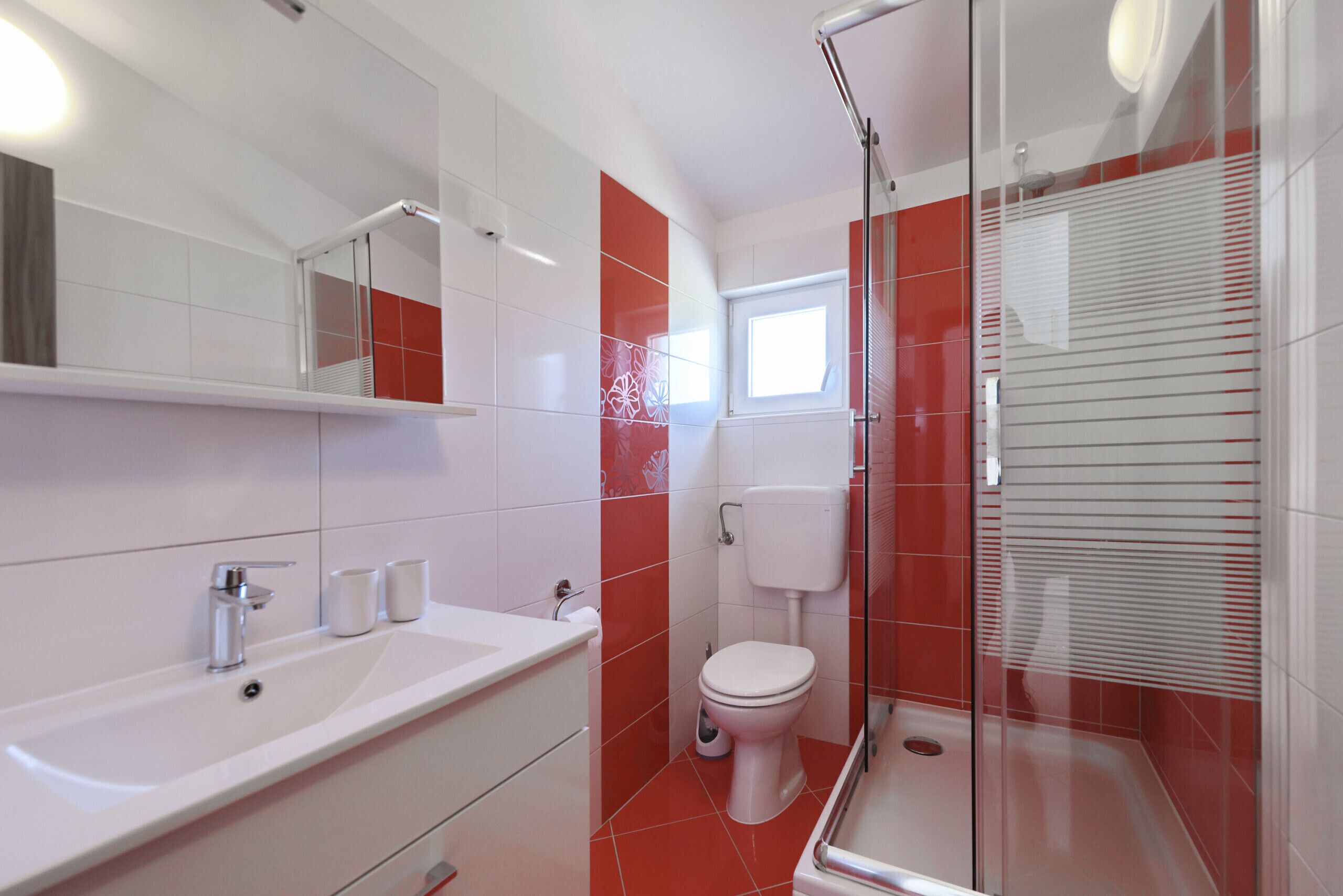 Ein modernes Badezimmer mit einer gläsernen Dusche, einem weißen Waschbecken und einer Toilette.