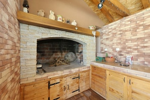 Eine Küche mit Kamin aus Stein, Holzschränken und einer Ziegelwand.