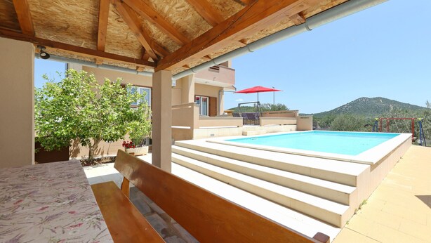 Un espace extérieur abrité doté d’une piscine, d’un escalier menant à un balcon et d’un banc en bois.