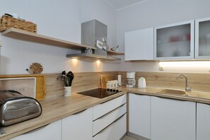 Eine moderne Küche mit weißen Schränken, einer Holzarbeitsplatte, einem eingebauten Herd und einem Edelstahl-Toaster.