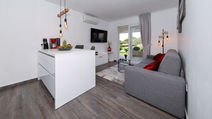 Ein moderner Wohnraum mit Kücheninsel, grauem Sofa und Wand-Fernseher.