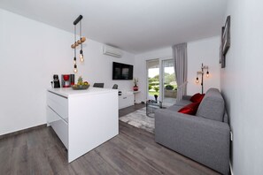 Ein moderner Wohnraum mit Kücheninsel, grauem Sofa und Wand-Fernseher.