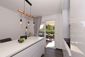 Eine moderne Küche mit weißer Arbeitsplatte, Pendelleuchten und Blick auf eine Terrasse.