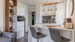 A modern kitchen with a central island, bar stools, a built-in microwave, and pendant lighting. - Apartment Suva Punta 2 by the Sea (Vir)