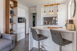 A modern kitchen with a central island, bar stools, a built-in microwave, and pendant lighting. - Apartment Suva Punta 2 by the Sea (Vir)