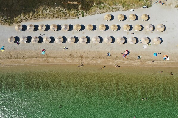 An aerial view of a beach with rows of sun umbrellas and people scattered along the shore. - Apartment Sandstrand 2 with Sea View (Nin)