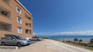 Un edificio con diversi balconi, un vialetto sterrato e vista su un corpo d'acqua con montagne sullo sfondo.