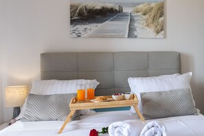 A neatly made bed with a breakfast tray, pillows, and a framed picture on the wall. - Apartment Sandstrand 2 with Sea View (Nin)
