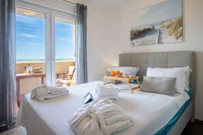 A hotel room with a bed, a breakfast tray, a painting, and a view of the beach. - Apartment Sandstrand 2 with Sea View (Nin)