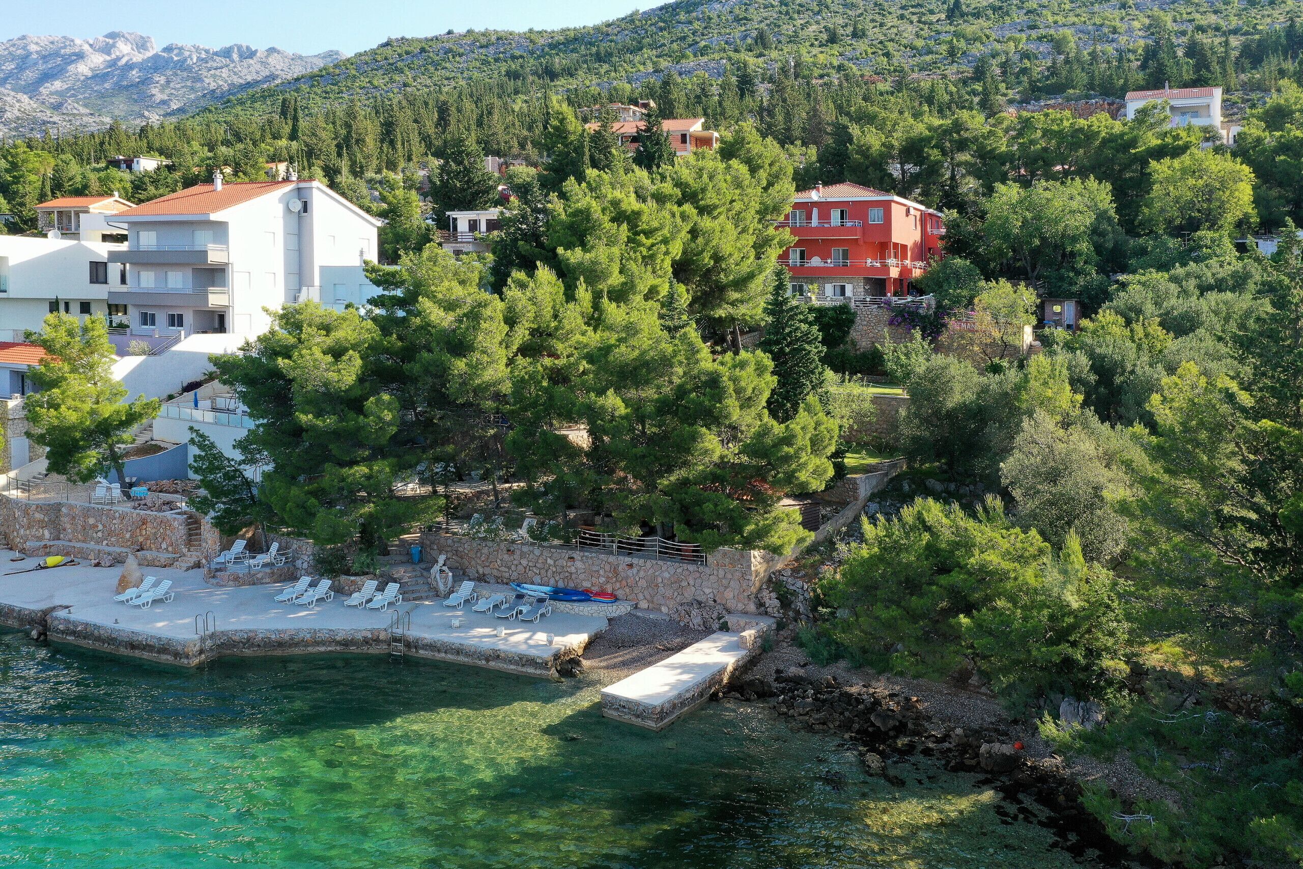 Ein Küstenanwesen mit Swimmingpool, Liegestühlen und einer Steinmauer.