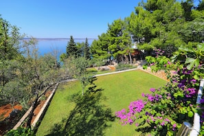 Ein Garten mit Rasen, Bäumen und Blick auf das Meer.