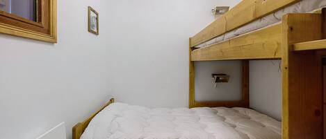Une chambre avec un lit superposé, comprenant un lit simple en bas et un autre lit superposé en haut.
