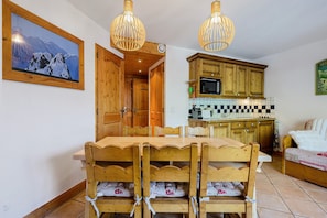Una mesa de comedor de madera con sillas, una cocina con armarios de madera y un cuadro en la pared.