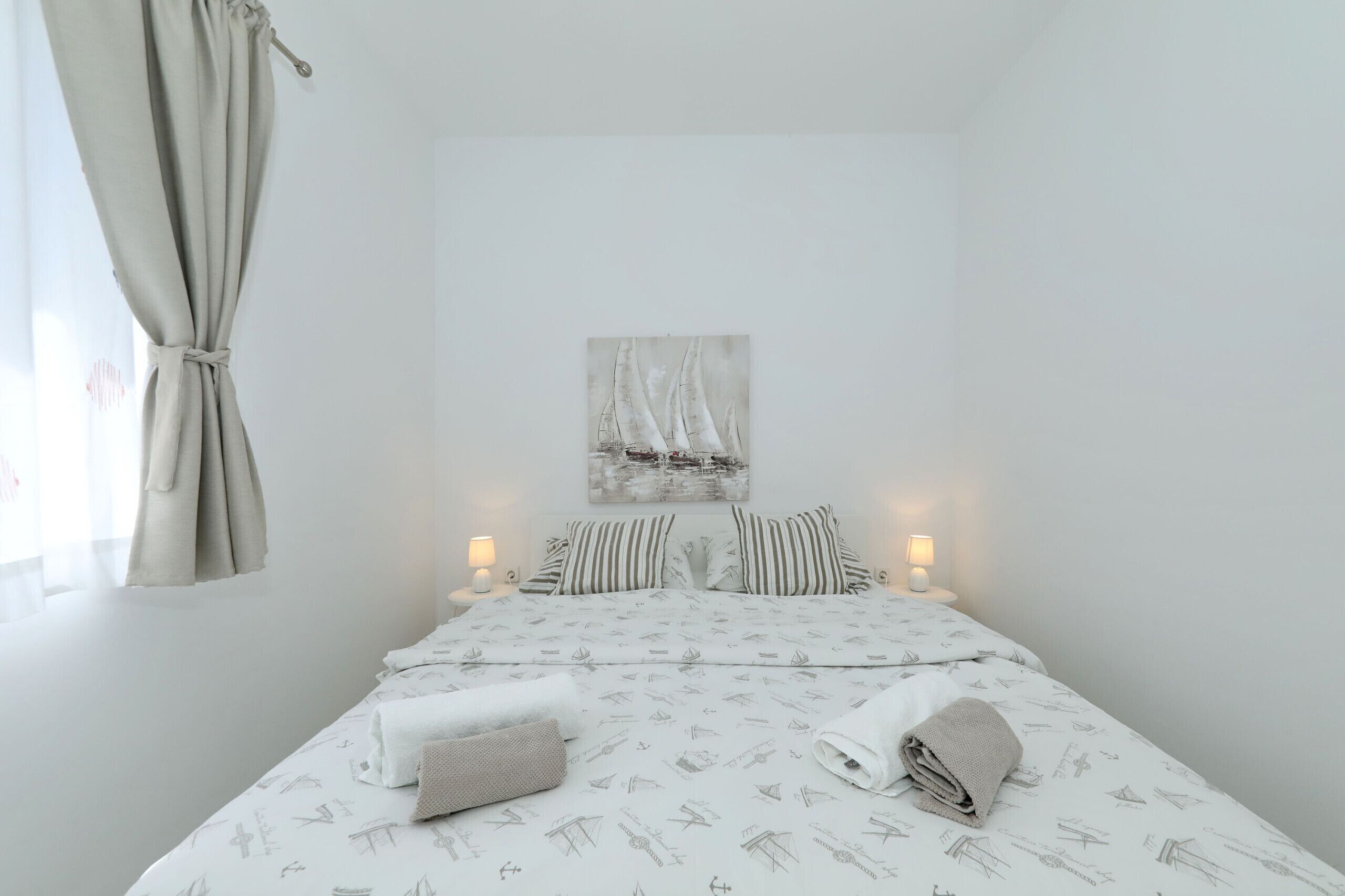 A neatly made bed with striped pillows, a wall-mounted artwork, and bedside lamps.