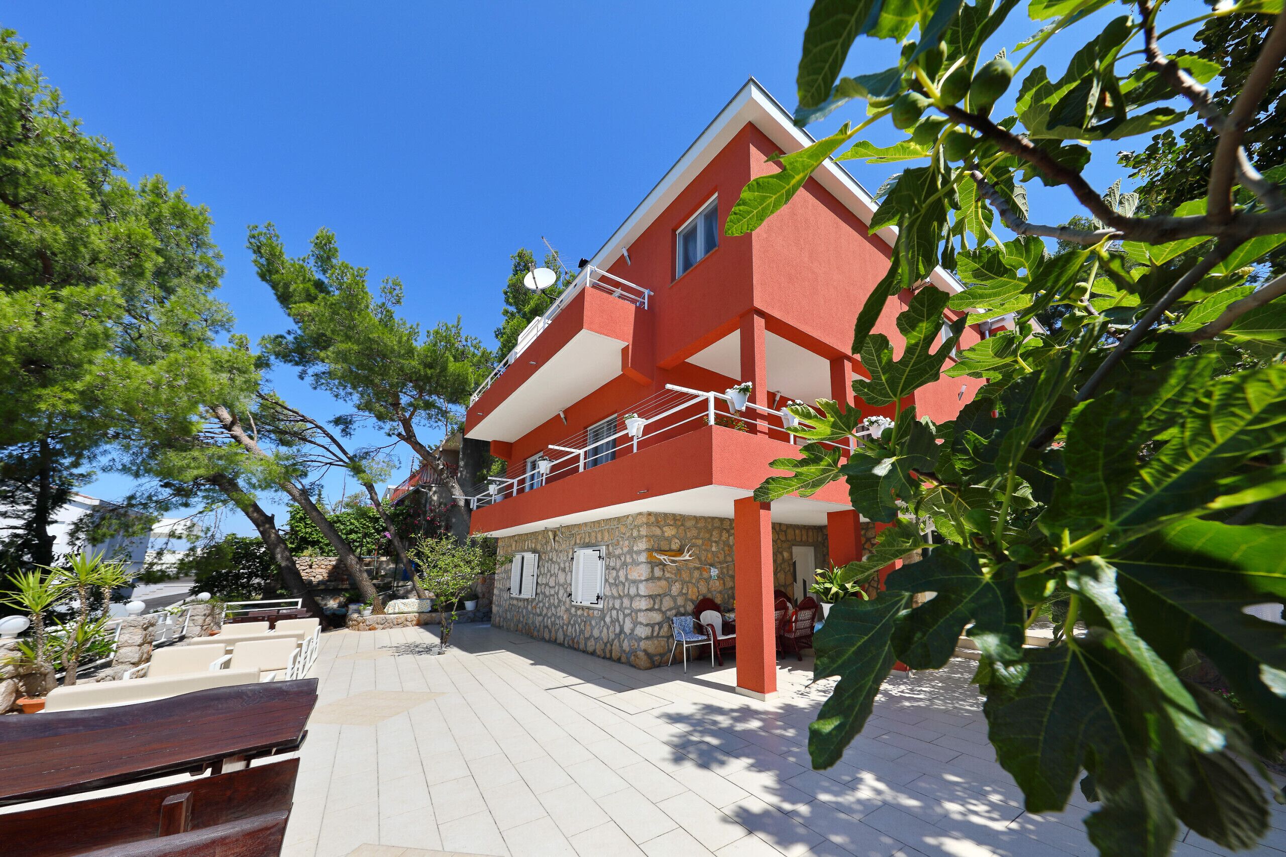 A red building with a stone facade, outdoor seating, and a clear blue sky.