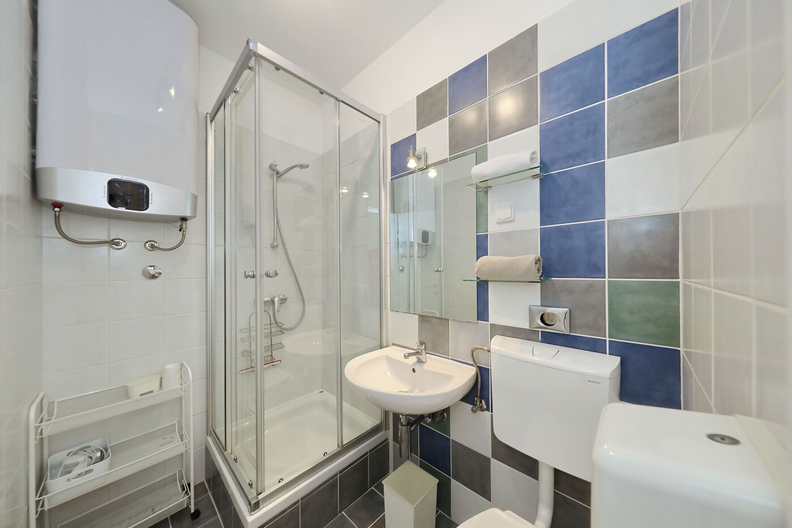 Ein modernes Badezimmer mit einer ein Glaswand trennenden Dusche, einem weißen Waschbecken und einer Toilette.