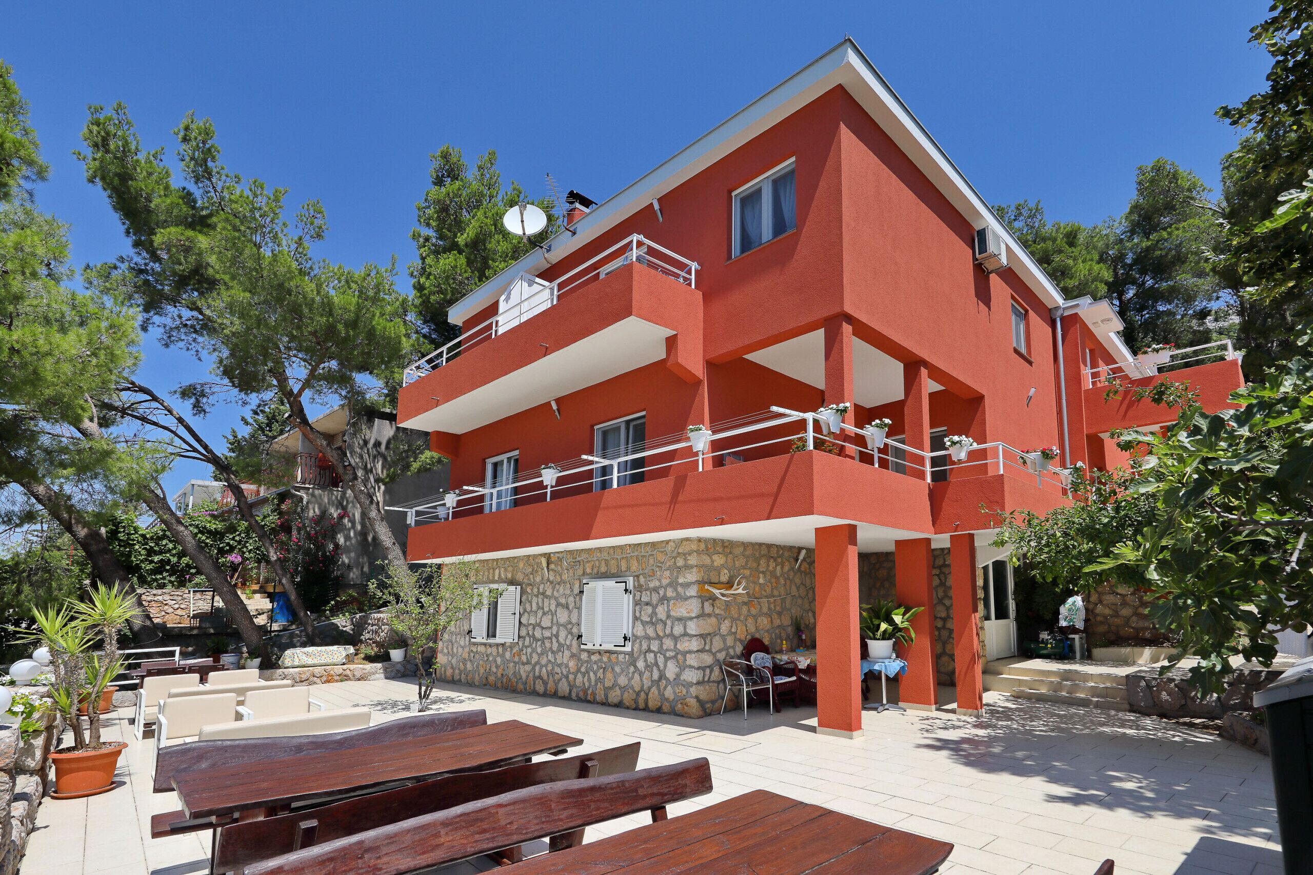 Ein rotes Gebäude mit einer Stein-Fassade, Außenplätzen und einem Balkon.