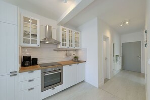 Eine moderne Küche mit weißen Schränken, Edelstahlgeräten und einer Holzausziehtafel.