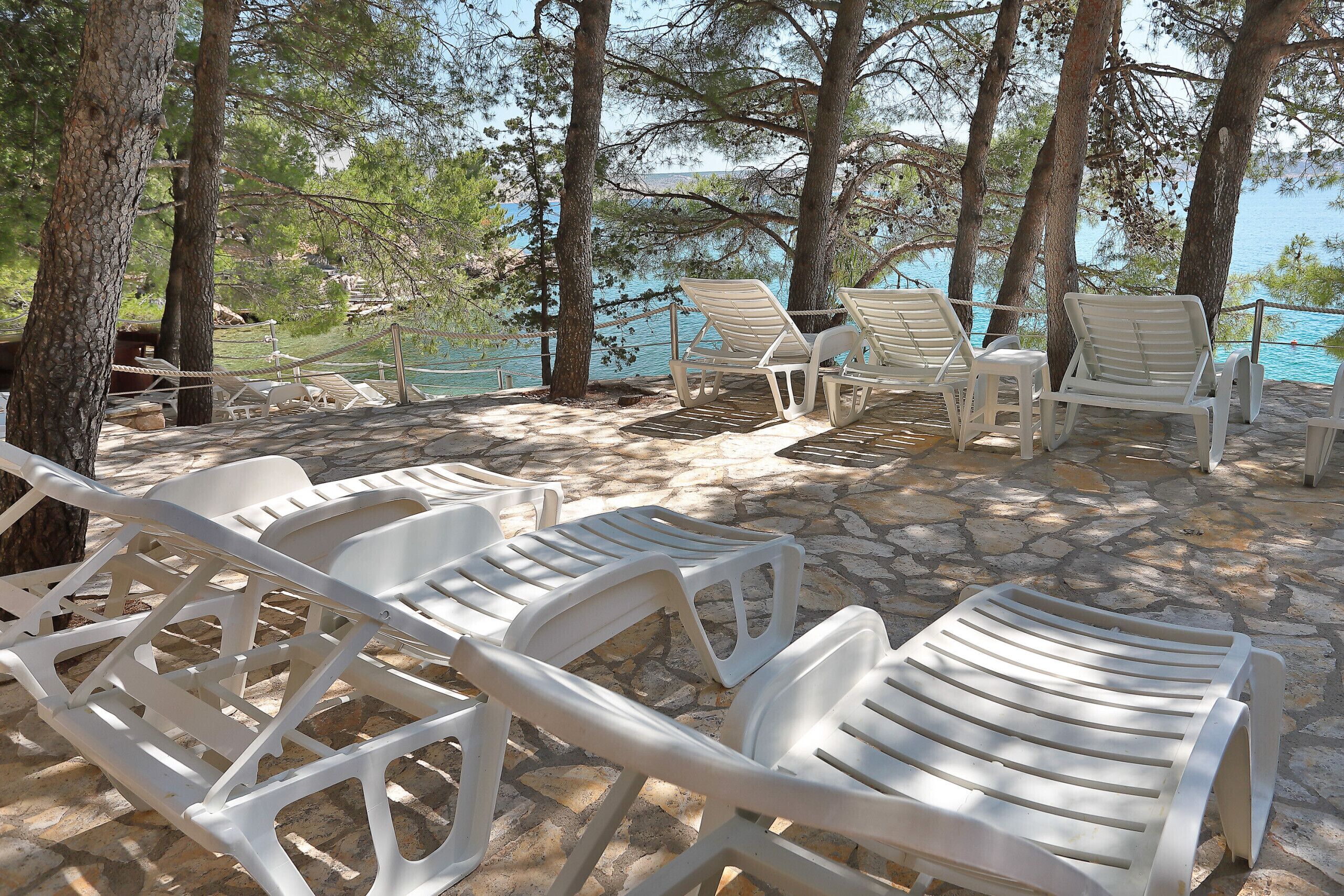 Outdoor lounge chairs, a stone pathway, and a view of the sea.