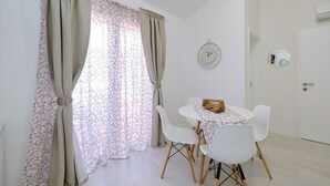 Une pièce comprenant une table à manger, des chaises, des rideaux, une horloge et un appareil de climatisation.