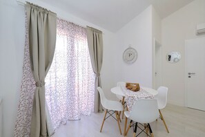 Ein Zimmer mit Esstisch, Stühlen, Vorhängen, einer Uhr und einer Klimaanlage.