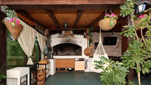Une cuisine rustique avec un four en briques, des armoires en bois et des paniers suspendus remplis de fleurs.
