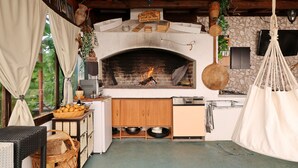 Une cuisine rustique avec une cheminée en briques, des armoires en bois et un luminaire suspendu.