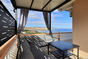 A balcony with a sofa, a table, and curtains. - Apartment Marina No.2 with Sea View (Rovanjska)