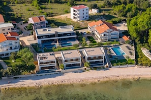 Ein Hotel an der Küste mit mehreren Gebäuden, einem Schwimmbad und einem Strandbereich.