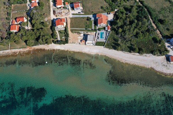 An aerial view of a coastal area with houses, a swimming pool, and a beach. - Apartment Suva Punta 4 by the Sea (Vir)