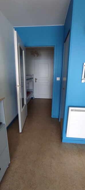 Ein schmaler Flur mit einem Etagenbett, einer weißen Tür und einem weißen Schrank.